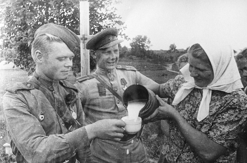 1944. Riga (sekarang Latvia). Seorang perempuan menuangkan susu dari sebuah kendi kepada seorang prajurit Tentara Merah.