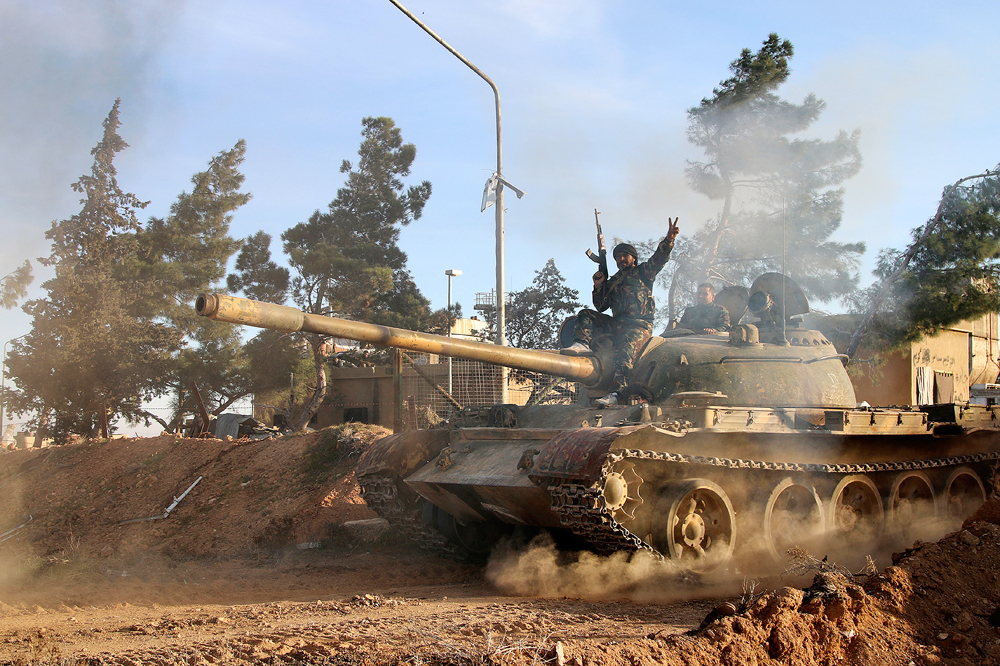 Seorang pejuang relawan dengan pasukan Pemerintah Suriah duduk di atas tank di Provinsi Raqqa, Suriah.