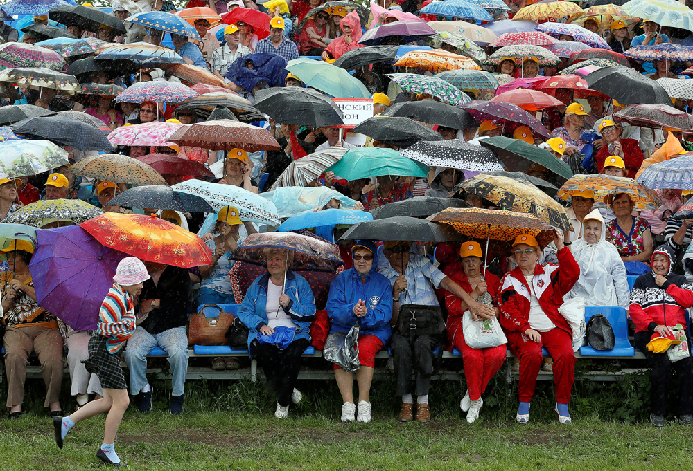 Зрители на „Фестивала на възможностите“ – ежегодно спортно и танцувално мероприятие за хора на възраст над 55 години, под дъжда в сибирския град Красноярск.