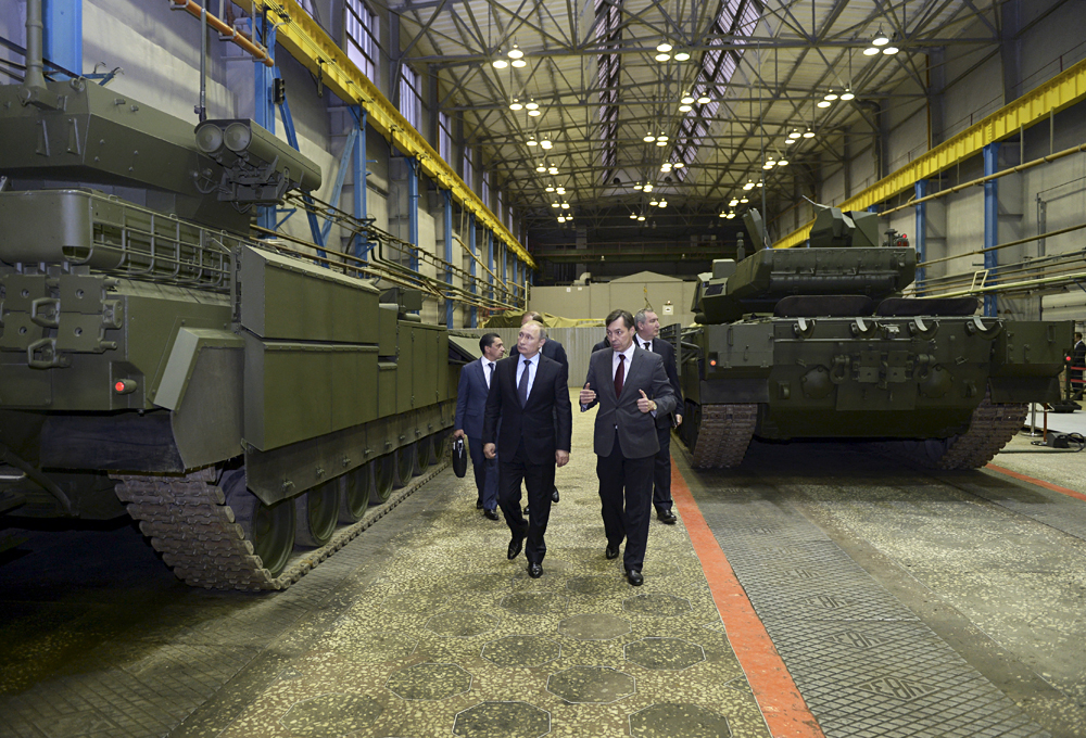Presiden Rusia Vladimir Putin (kiri) mendengarkan Andrei Terlikov, Kepala Biro Desain Ulravagonzavod, saat keduanya mengecek kendaraan tempur infanteri dengan Platform Tempur Universal Armata dan tank tempur utama T-14 Armata di pabrik Uralvagonzavod di kota Nizhny Tagil, 25 November 2015.