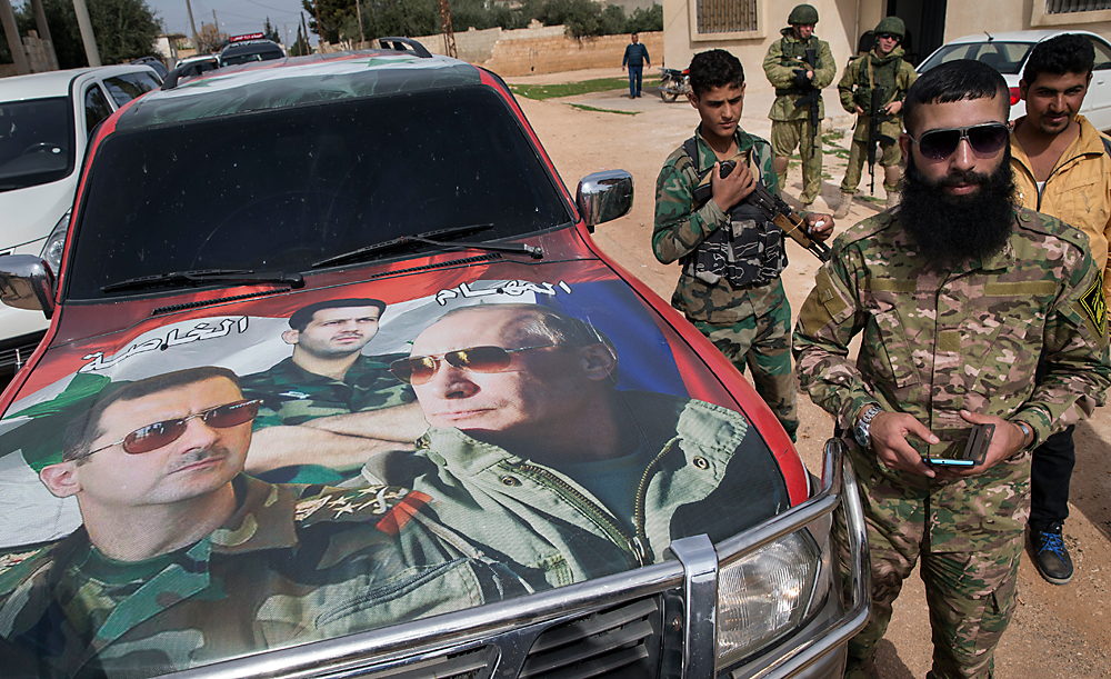 Soldados sírios passam por carro adesivado com imagens de Assad e Pútin