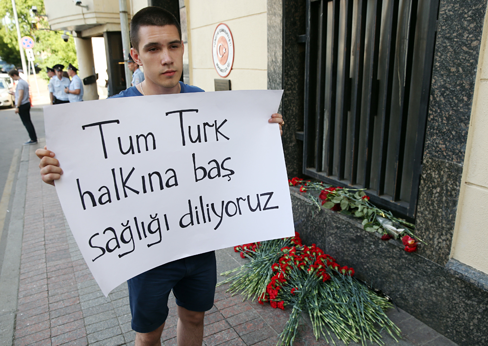Seorang pemuda memegang poster bertulisan "Tum Turk halkina bas sagligi diliyoruz" di pintu masuk Kedutaan Turki di Moskow pasca-serangan Bandara Istanbul, 28 Juni 2016. 