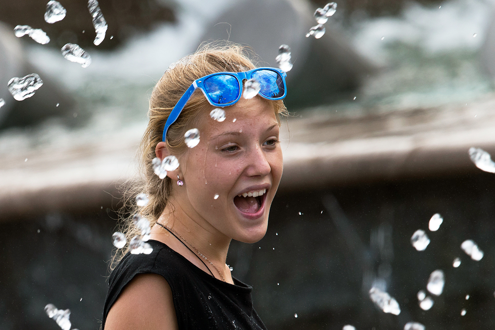 A girl cools herself at a fountain near the Kremlin Wall in Moscow, Russia