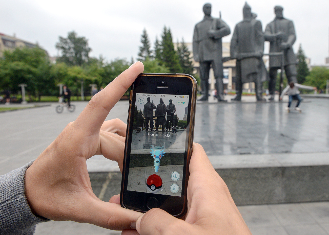 Покемон Го, играта од Нинтендо, на мобилен телефон во паркот од другата страна на улицата од операта Новосибирск.