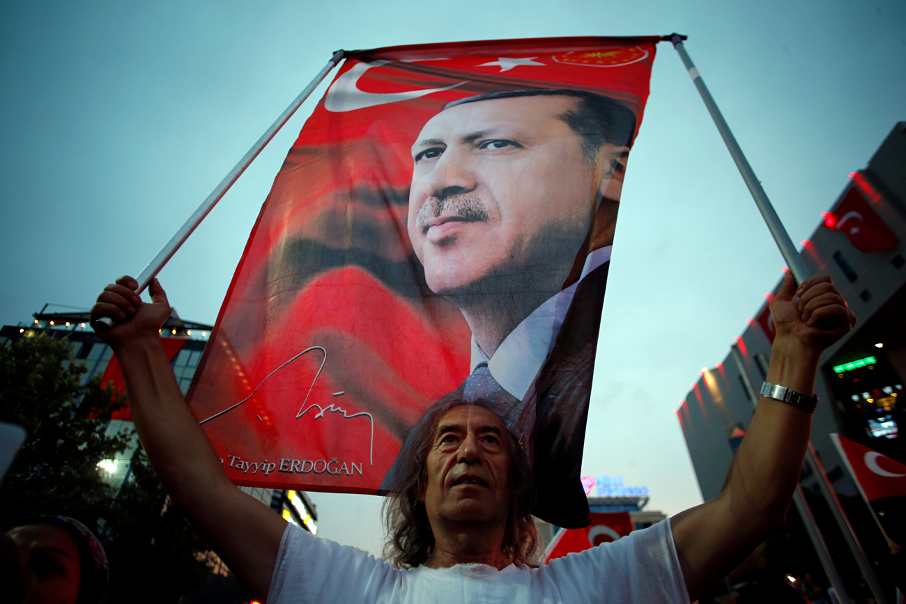 A supporter holds a flag depicting Turkish President Tayyip Erdogan during a pro-government demonstration in Ankara, Turkey, July 20, 2016. 