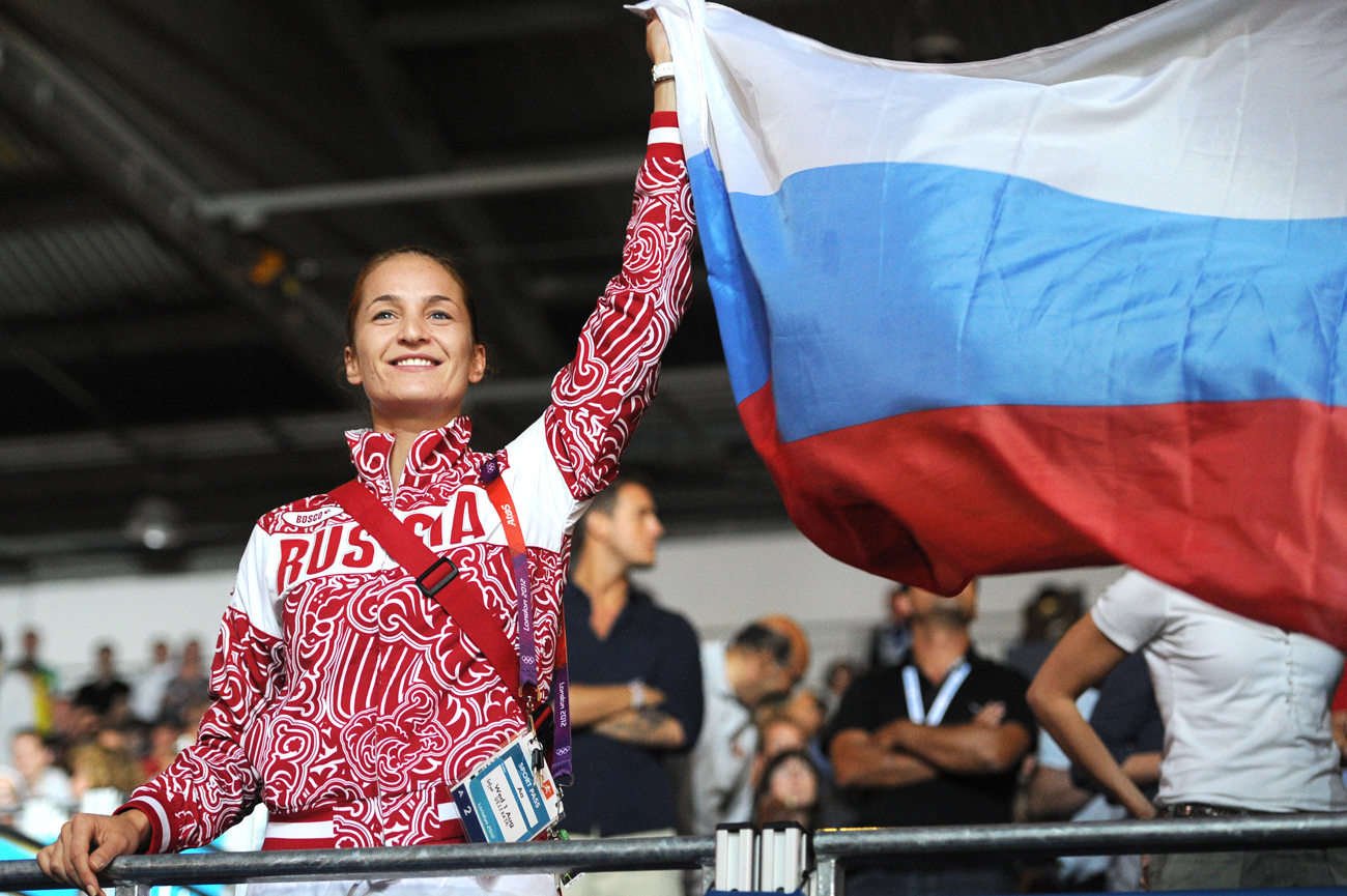 Atlet anggar Rusia Sofya Velikaya memegag erat bendera Rusia saat upacara pemberian medali pada Olimpiade Musim Panas London 2012. Tim Rusia memenangkan medali perak.