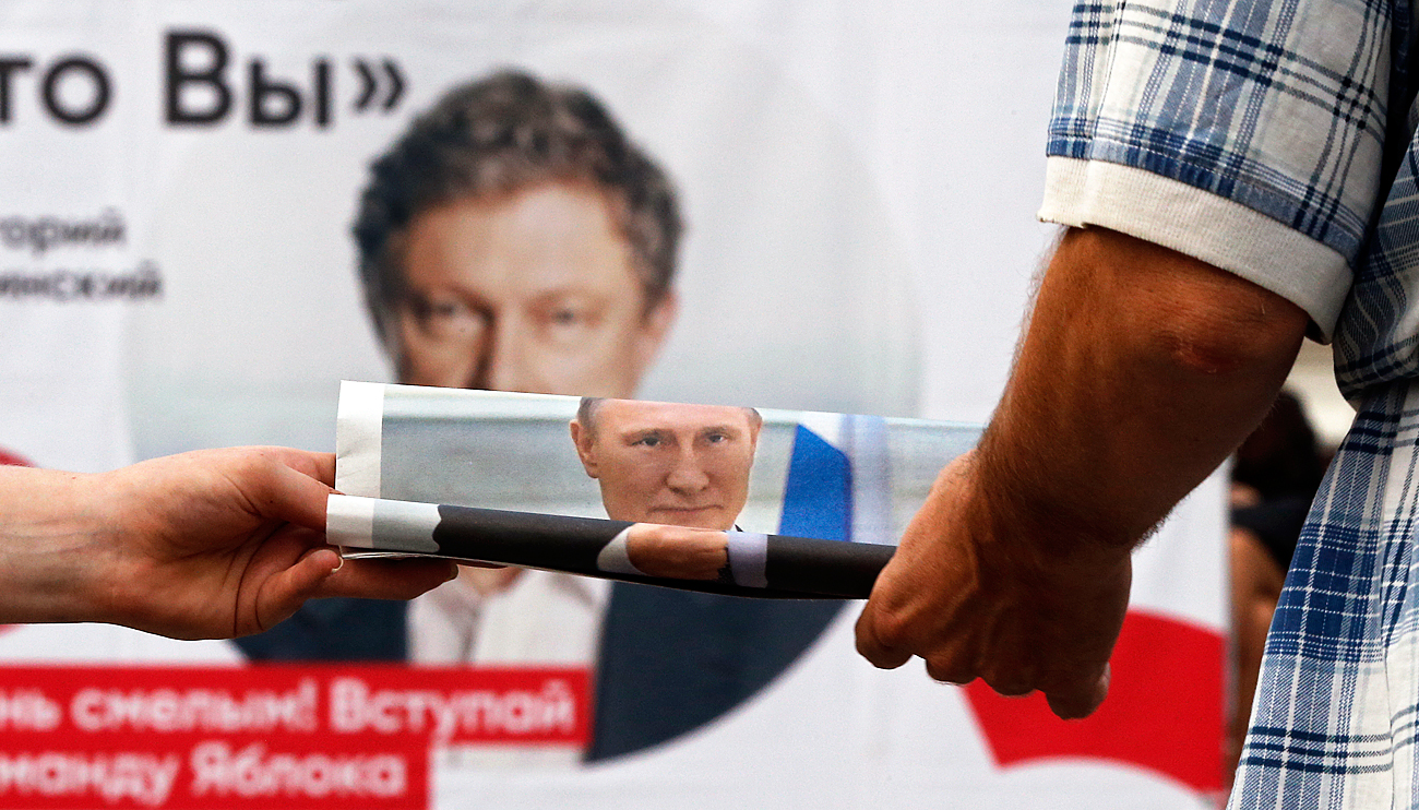 Un agitateur du parti Russie unie devant une banderole du parti Yabloko (opposition). 