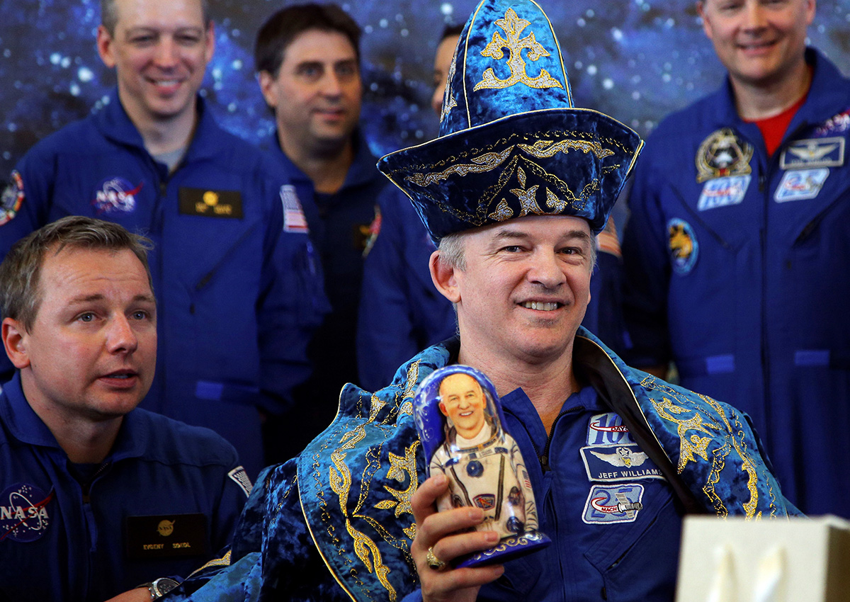 ... Или астронавт от НАСА. / Джеф Уилямс, член на екипажа на Международната космическа станция, облечен в казашка носия, държи матрьошка на пресконференция в Казахстан, 2016 година.