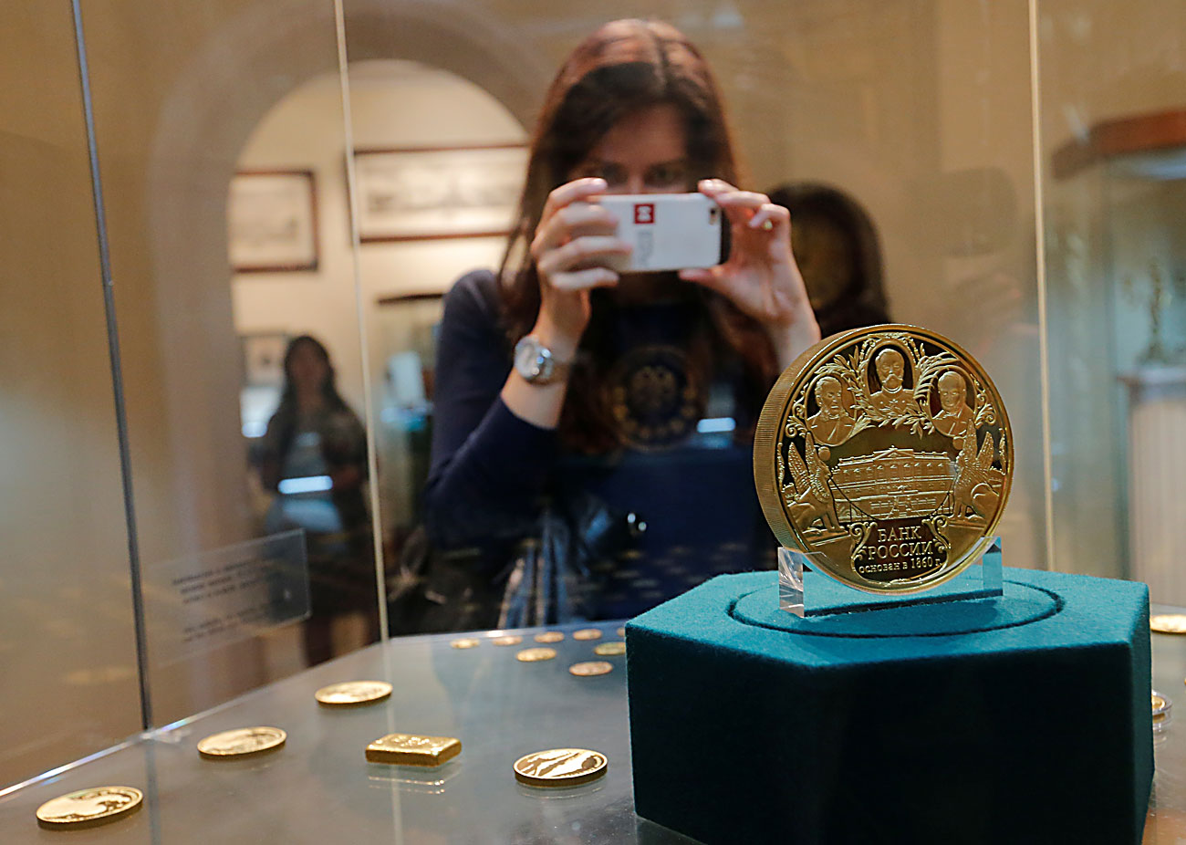Посетител ја фотографира комеморативната монета на руска рубља од колекцијата на музејскиот и изложбен фонд во седиштетото на Централната банка во Москва, Русија.