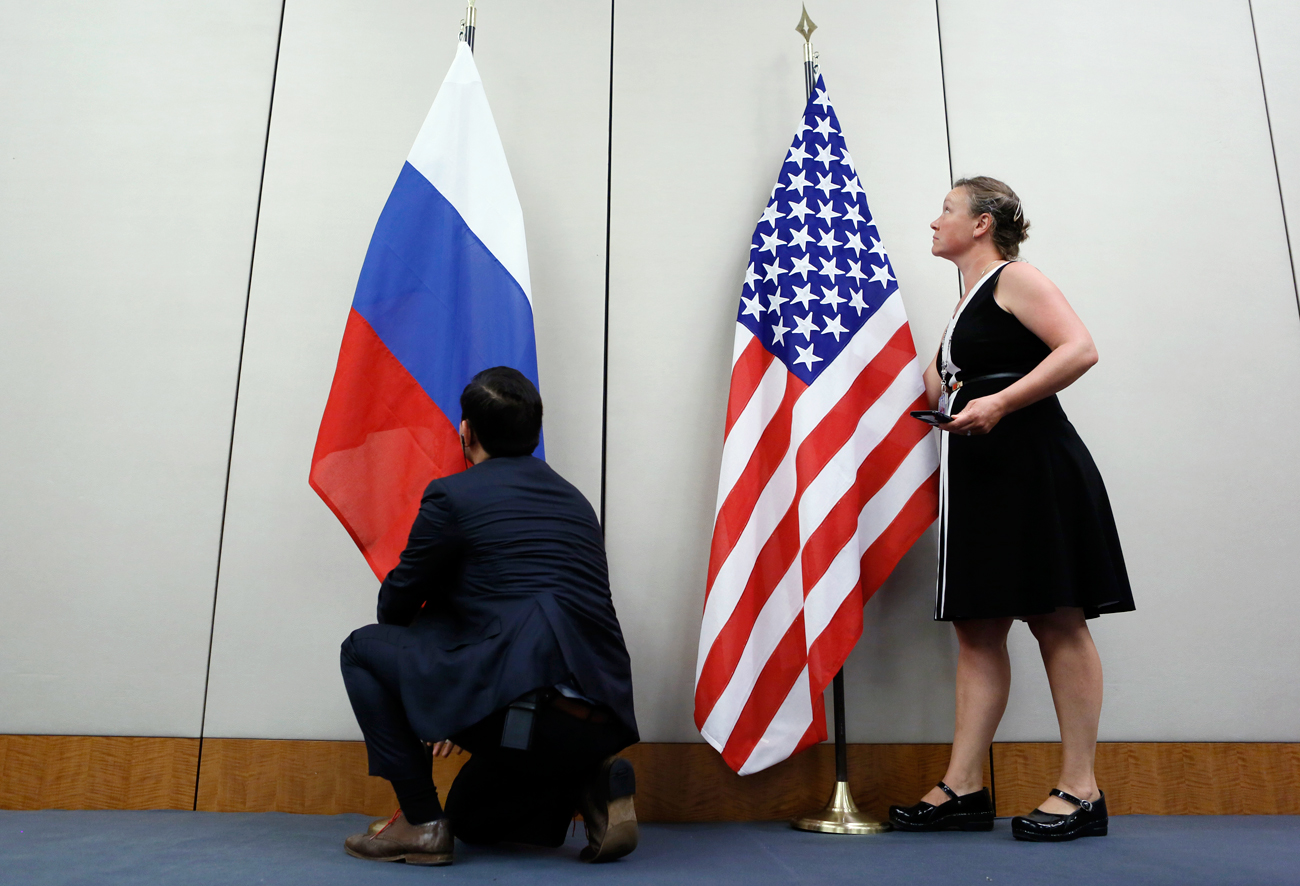 Seorang staf memasang bendera Rusia di samping bendera AS sebelum konferensi pers setelah pertemuan antara Menteri Luar Negeri AS John Kerry dan Menteri Luar Negeri Rusia Sergey Lavrov di Jenewa, Swiss, 26 Agustus 2016.