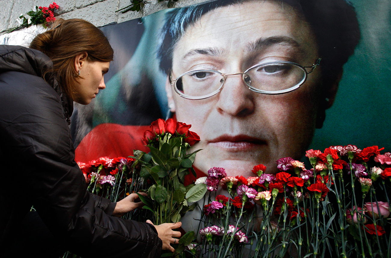 Pessoas colocam flores diante de retrato de Politkóvskaia em Moscou. Jornalista investigativa foi morta há exatos 10 anos.