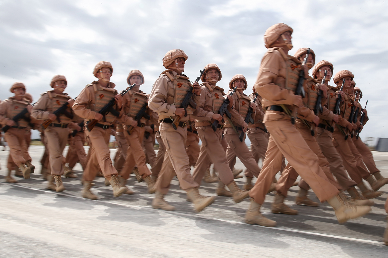 Tentara Rusia berbaris dalam formasi selama latihan untuk Parade Hari Kemenangan di Pangkalan Udara Hmeimim, Suriah.