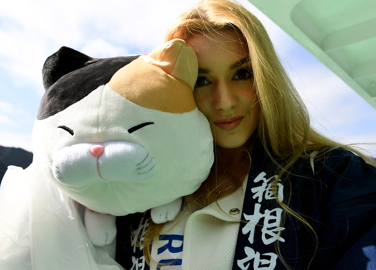Alisa Manenok, miss Rusia, muestra el souvenir de un gato de peluche al subir a un barco en Hakoke, Japón, donde competirá con 60 mujeres por obtener la corona de Miss Internacional.