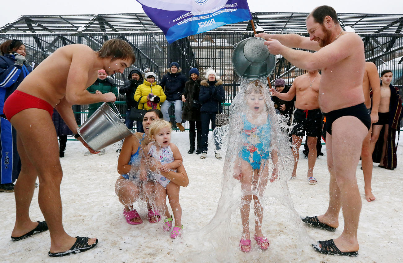 Visitors watch as members of a local winter swimmers club pour buckets of cold water over their daughters, 7-year-old Liza Broverman and 2-year-old Alisa Smagina during a celebration of Polar Bear Day at the Royev Ruchey zoo, with the air temperature at about minus 5 degrees Celsius (23 degrees Fahrenheit), in Krasnoyarsk, Russia, November 27, 2016.