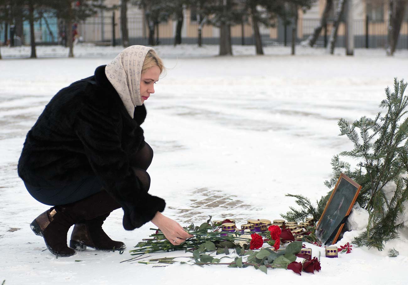 Joven deja flores ante el retrato de Valeri Jalilov, director artísitico del Conjunto de Música y Danza Alexándrov de Ejército Ruso, cuyos miembros fallecieron en el accidente del Tu-154 cerca de Sochi. 