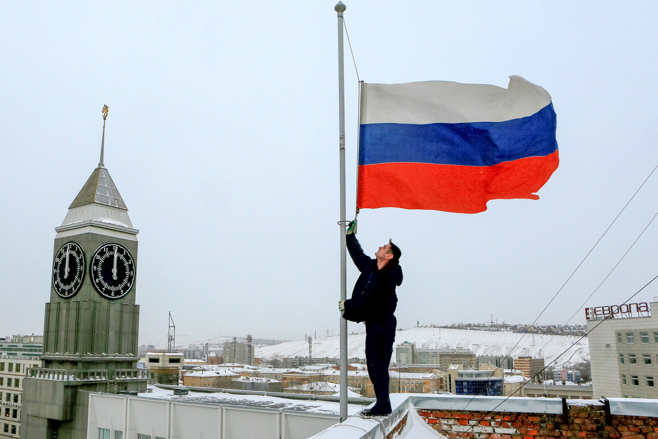 Работник го спушта знамето на Русија на половина копје на зградата на администрацијата по повод Денот на жалоста за загинатите во авионската несреќа на авионот Ту-154. 26 декември 2016, Краснојарск, Русија. 