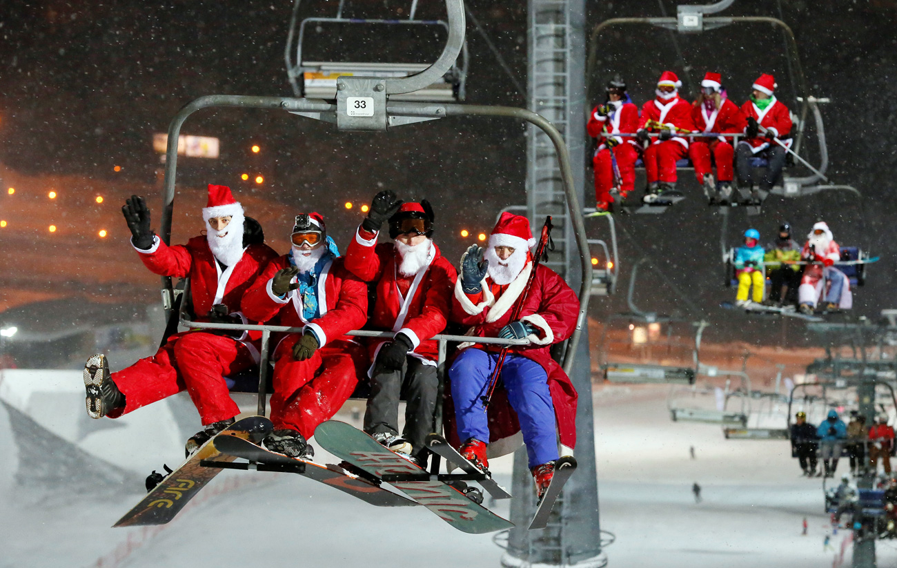 Скијачи и сноубордери облечени како Дедо Мороз и Снегурочка се возат со лифт за Ноќта на Дедо Мраз и Снегурочка по повод претстојната новогодишна прослава во скијачкиот центар „Боброви Лог“ во предградието на Краснојарск, Сибир, Русија.