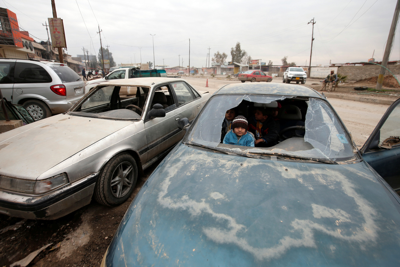 Anak-anak yang menjadi korban perang tampak dari kaca mobil yang pecah di  sebuah jalan di Mosul, Irak.