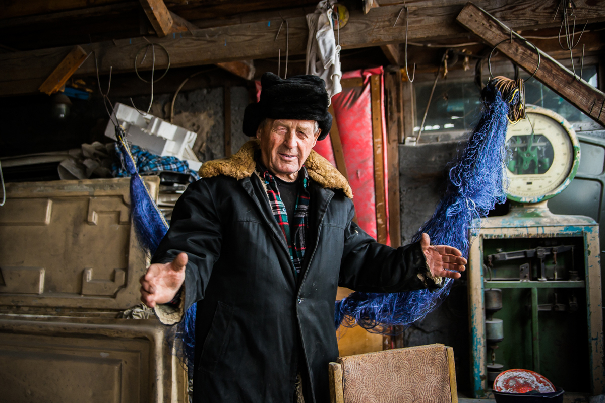 Nikolay Semenovich Konovalov, a fisherman from Khakassia, at his home, shows the size of the Siberian fish he has caught 