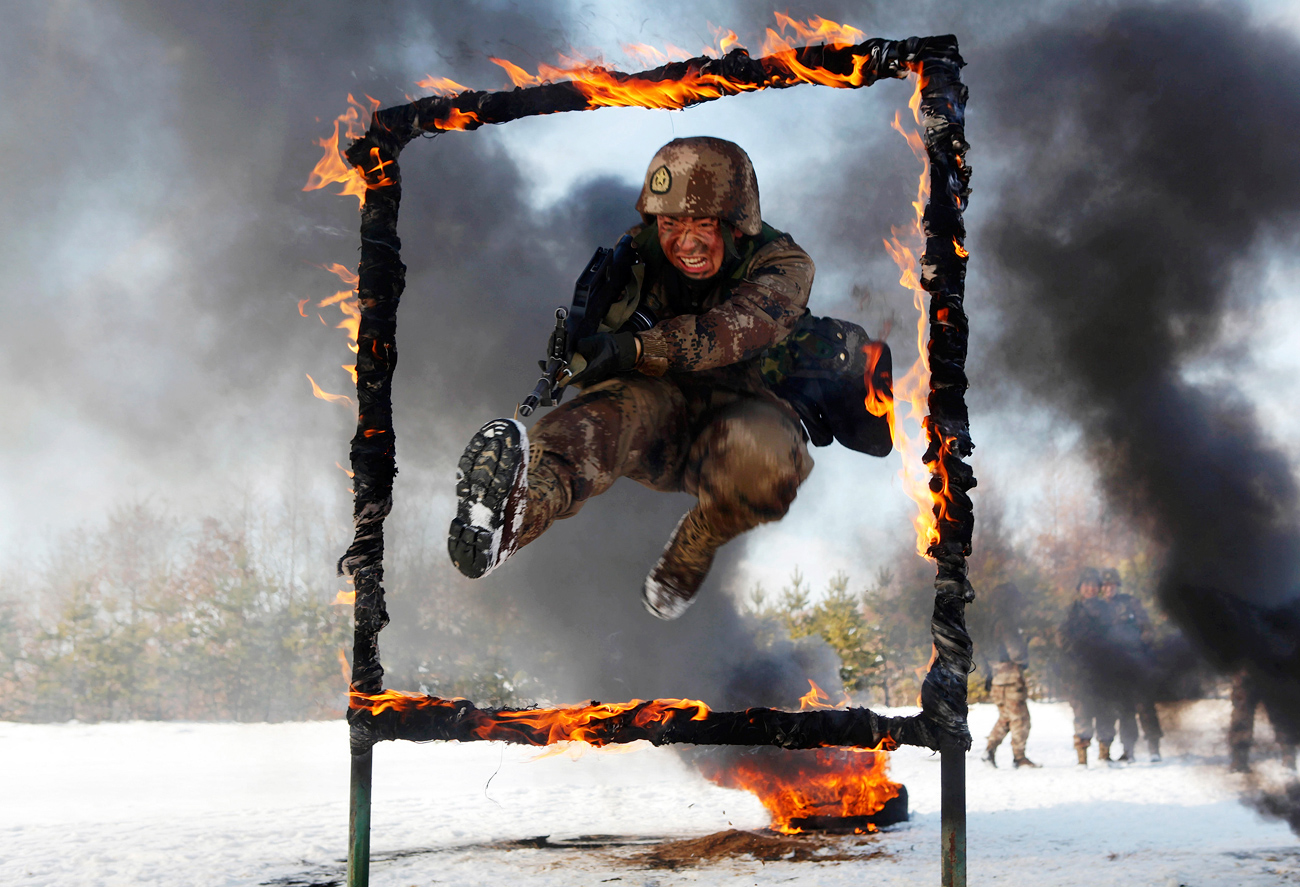 A People's Liberation Army soldier jumps over a burning obstacle during a training session on a snowfield, in Heihe, Heilongjiang province.