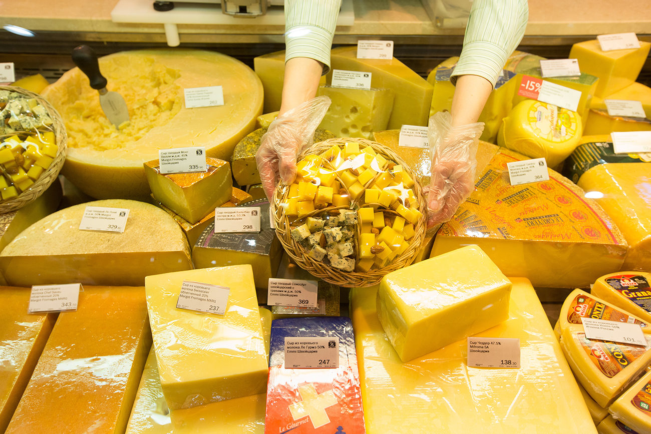 A worker arranges a display of cheeses, including imported products, at the delicatessen counter of an Azbuka Vkusa OOO, which translates as 'Elements of Taste,' supermarket at the Neglinnaya Plaza shopping center in Moscow, Russia.