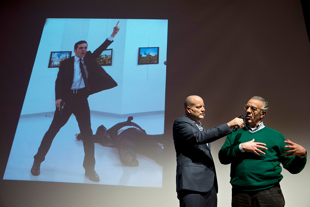 Il fotografo turco Burhan Ozbilici, a destra, interviene alla cerimonia di premiazione del World Press Photo 2017 ad Amsterdam; sullo sfondo, la sua foto “Un assassinio in Turchia”, vincitrice del primo premio.