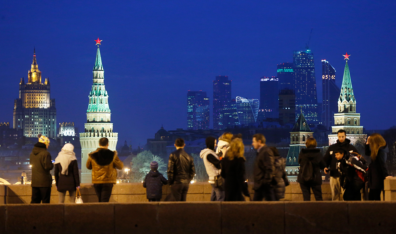 Хора на Големия Москворецки мост, от който се виждат кулите на Кремъл, сградата на Министерството на външните работи и бизнес центърът "Москва Сити".