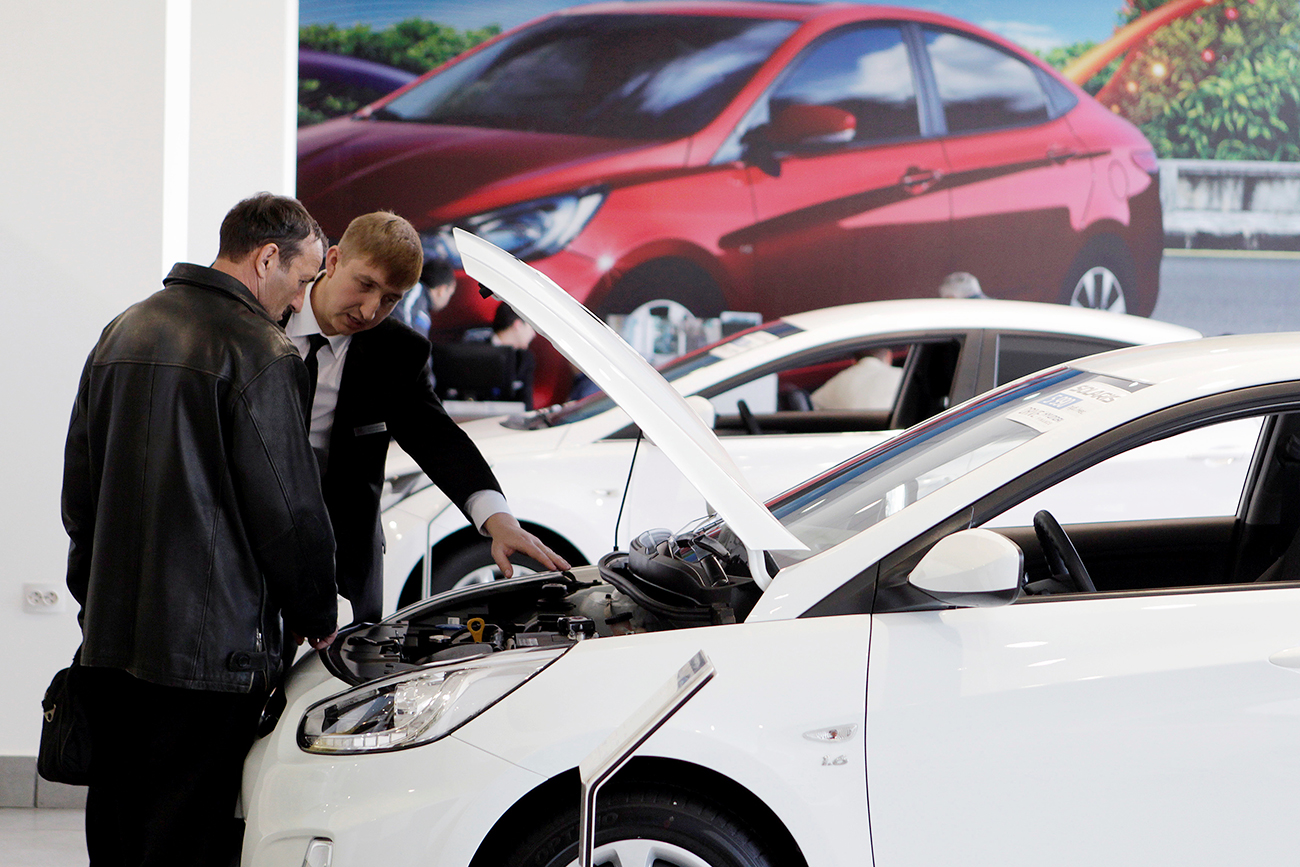 A customer listens to an employee near a Hyundai Solaris car at a showroom of a dealership in Stavropol, southern Russia.