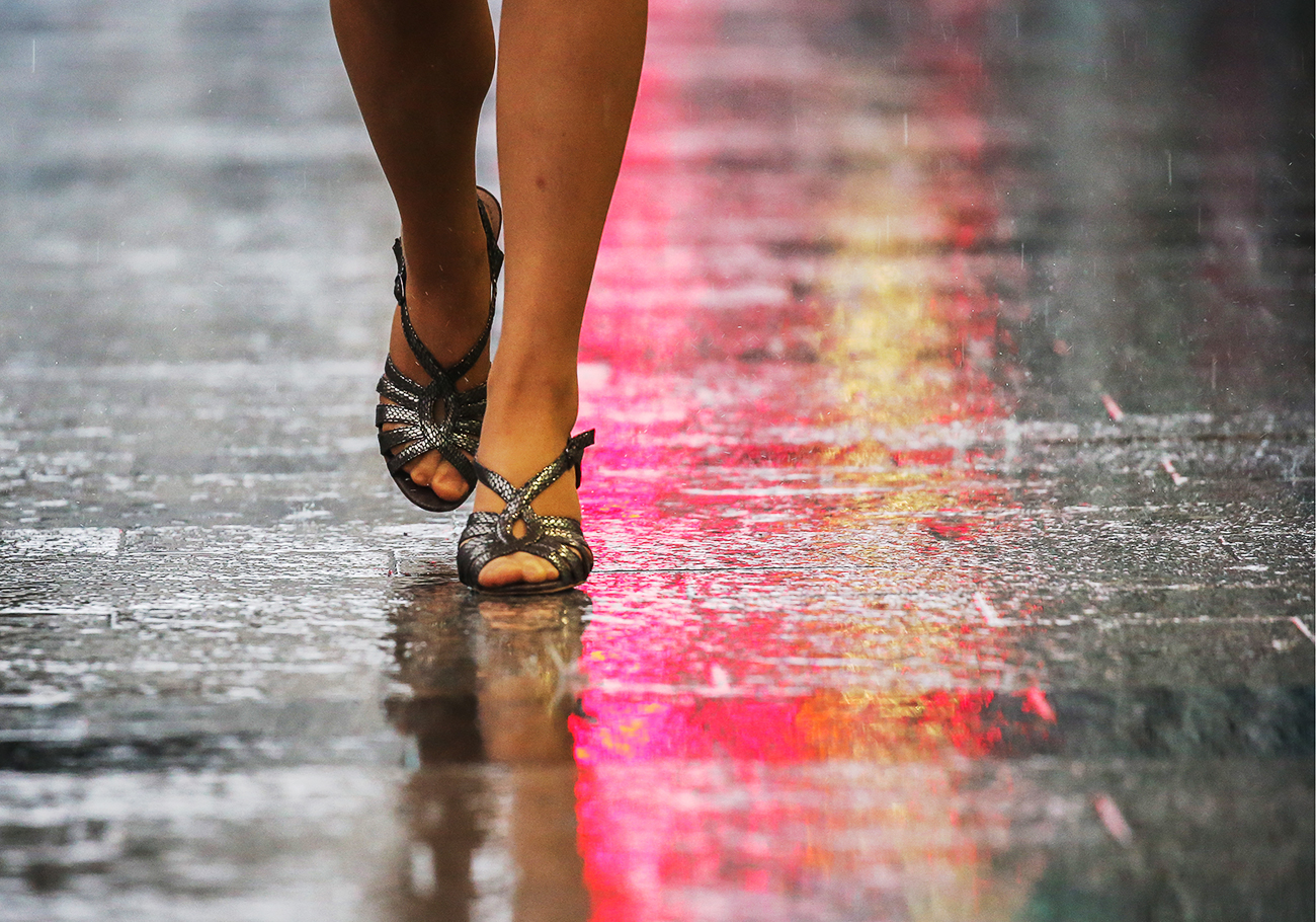 Una donna cammina sotto la pioggia in una strada di Mosca.