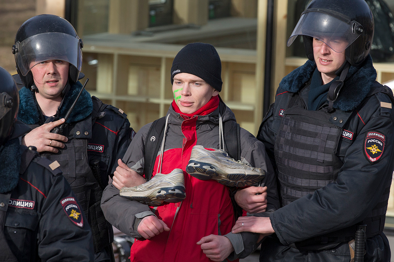 A protester with trainers on his neck, which has become a symbol of corruption, is detained in Moscow on March 26, 2017. 