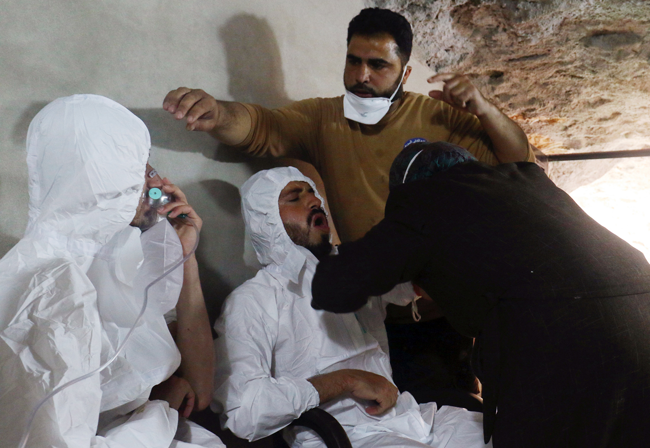 Seorang pria bernapas melalui masker oksigen sementara yang lainnya menerima perawatan, setelah apa yang digambarkan para petugas penyelamat sebagai serangan gas di kota Khan Sheikhoun di Provinsi Idlib yang dikuasai pemberontak, Suriah, 4 April 2017. 