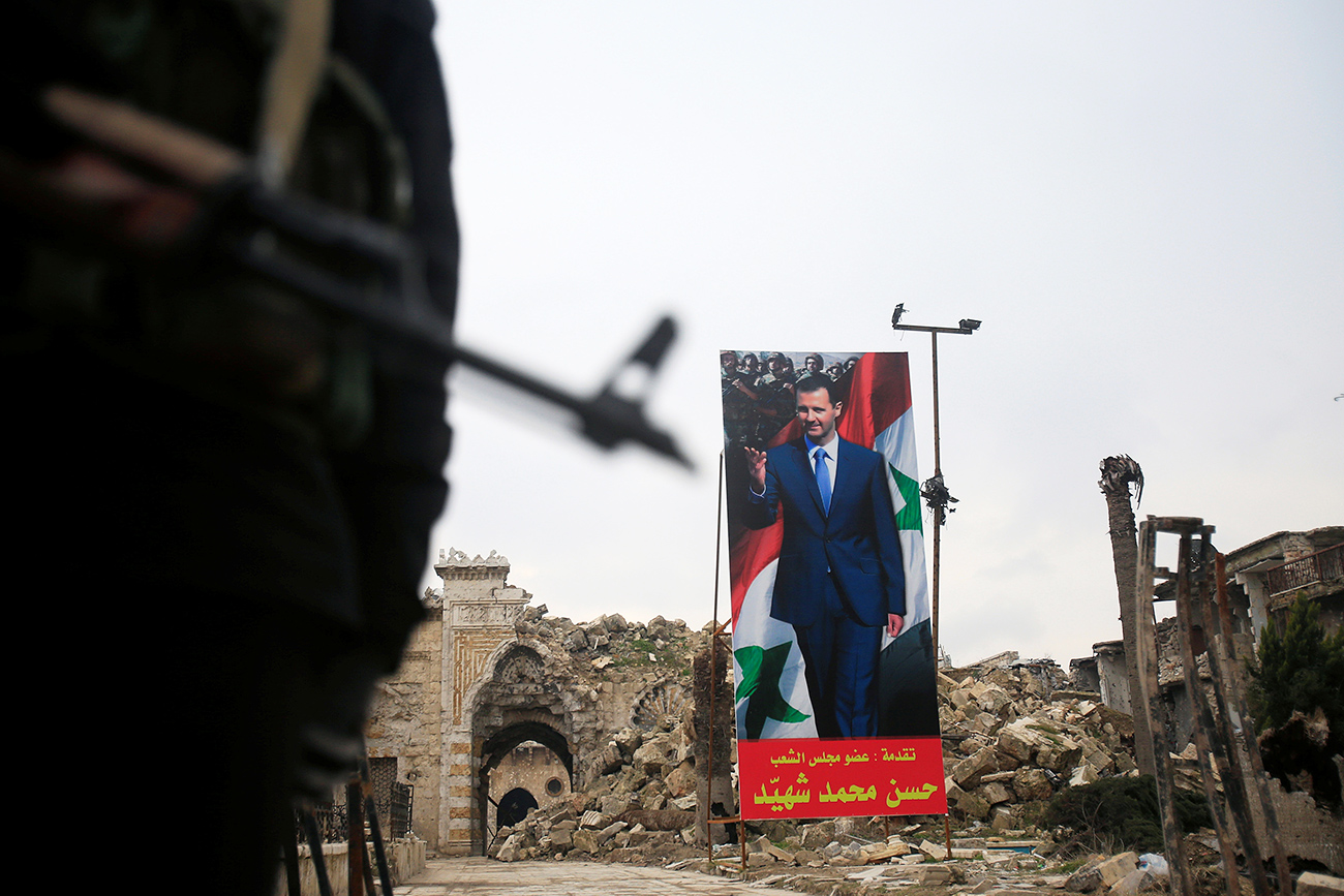 A Syrian army soldier stands guard as a poster depicting Syria's President Bashar al-Assad is seen in the background in the Old City of Aleppo, Syria January 31, 2017