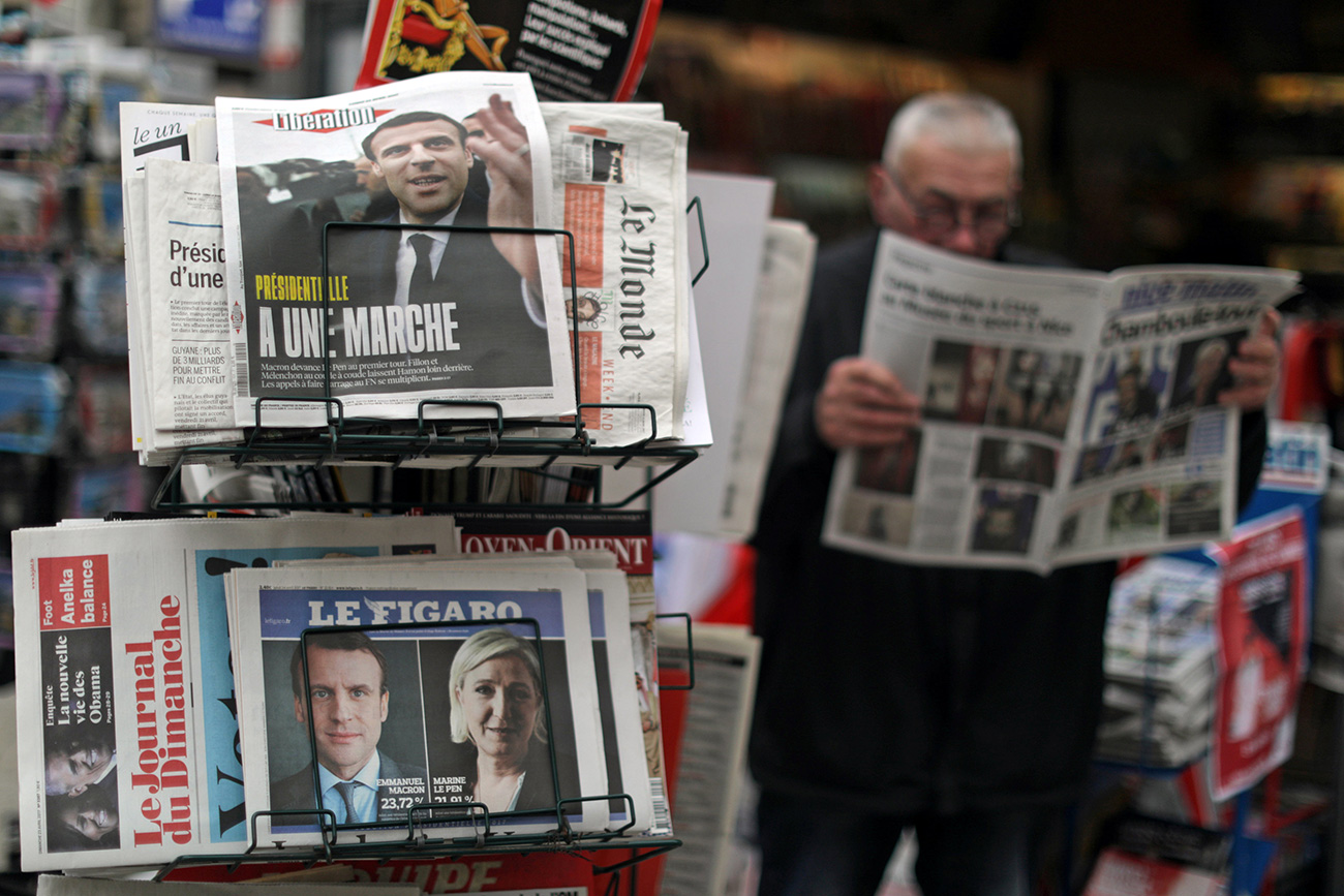 A man reads the local newspaper near a rack which displays copies of French daily newspapers with front pages about the results in France's Presidential election in Nice, France, April 24, 2017. 