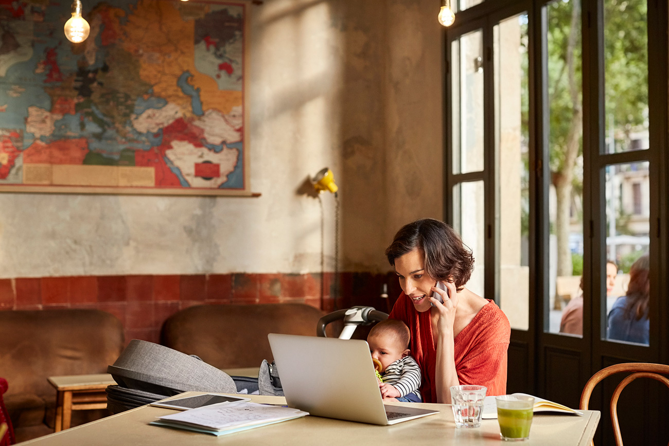Mother carrying baby using technologies at table