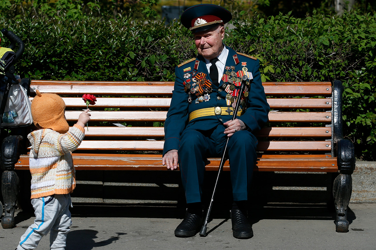 V središču pozornosti so veterani, ki so se tedaj borili v vojni. Na tej sliki vidimo prizor z 9. maja 2015, ko je deklica ponudila rožo slepemu veteranu v parku Gorki.