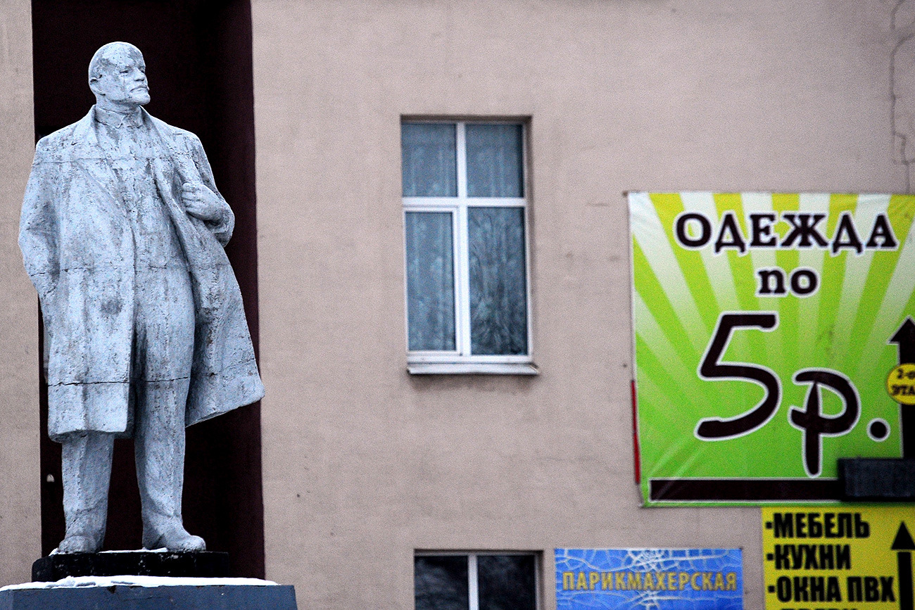 A statue of Russian revolutionary Vladimir Lenin in the Brest Region of Belarus. A poster on the building says "Clothes for five rubles" in Russian.