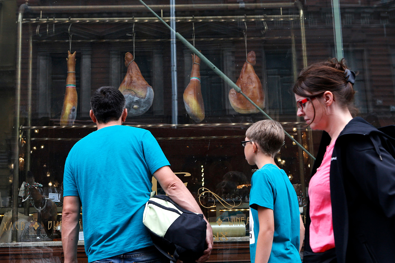 More than a half of Russian citizens support restrictions that Moscow imposed on food imports in response to Western sanctions. Photo: People pass by a shop window displaying Spanish ham for sale at a grocery store in St. Petersburg.