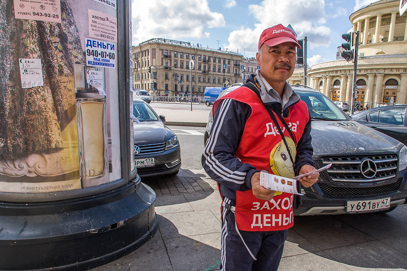 Жанровая фотография. Мужчина, рекламирующий услуги микрокредитования на улице города. Россия, Санкт-Петербург