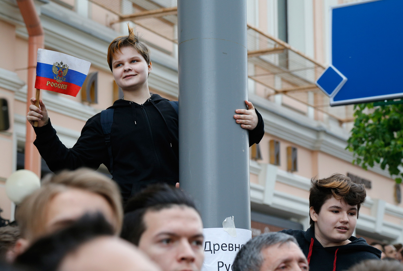 A young protestor holds up a Russian flag during a demonstration in downtown Moscow, Russia, Monday, June 12, 2017. Russian opposition leader Alexei Navalny, aiming to repeat the nationwide protests that rattled the Kremlin three months ago, has called for a last-minute location change for a Moscow demonstration that could provoke confrontations with police