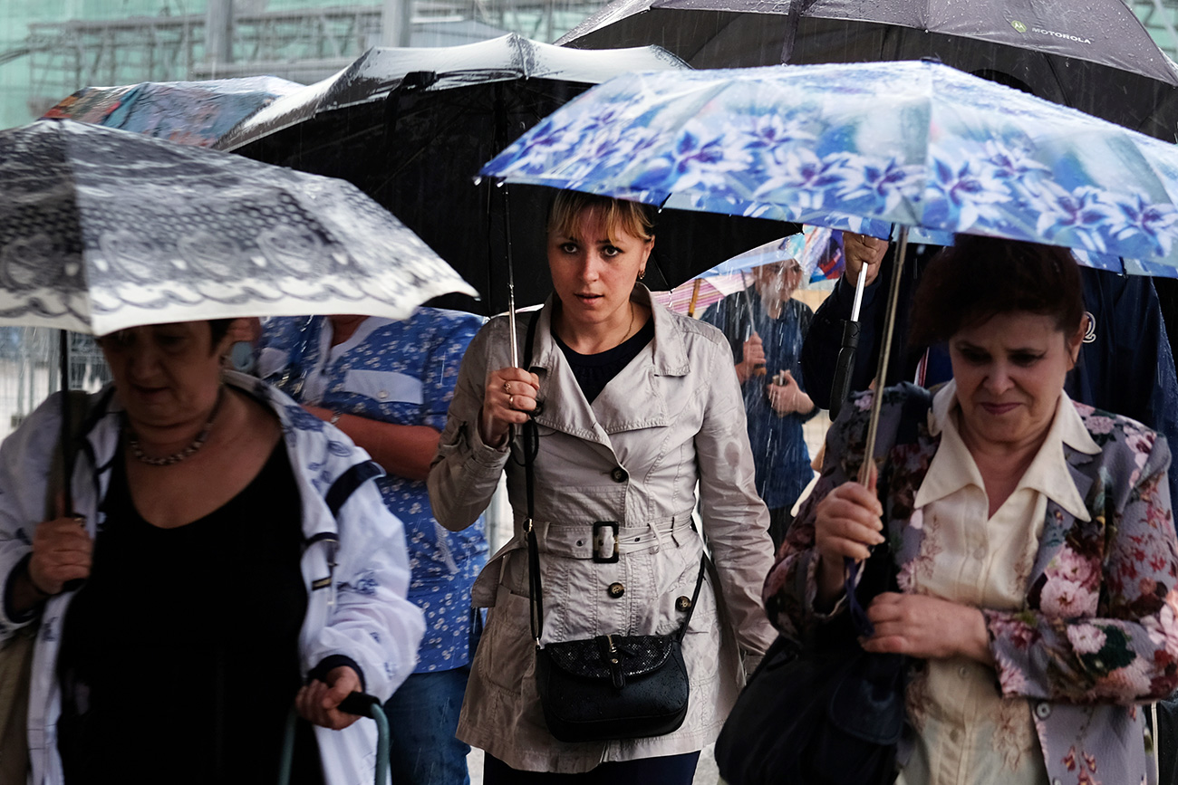 Passers-by in a street of Moscow during a rain.