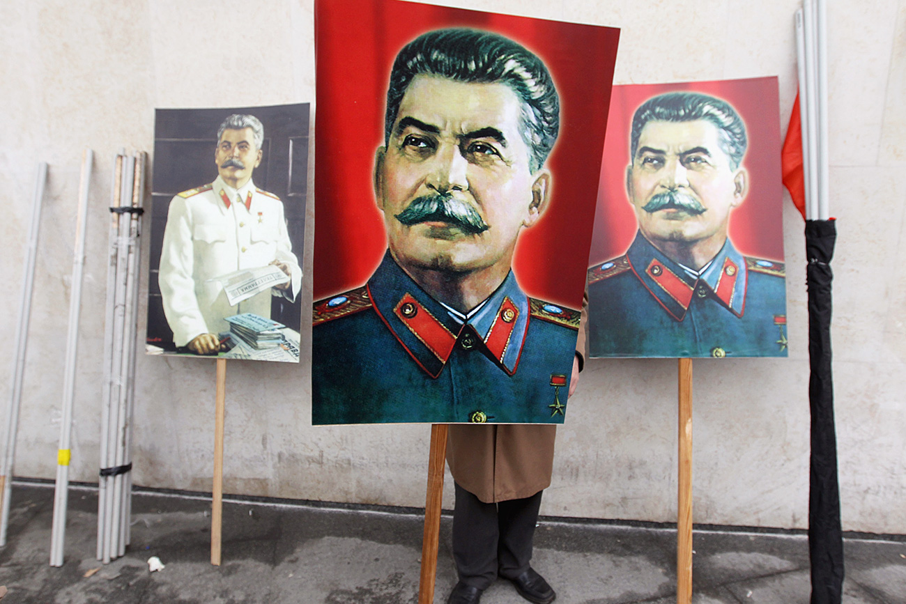 Seorang pendukung komunis mengangkat foto Josef Stalin.