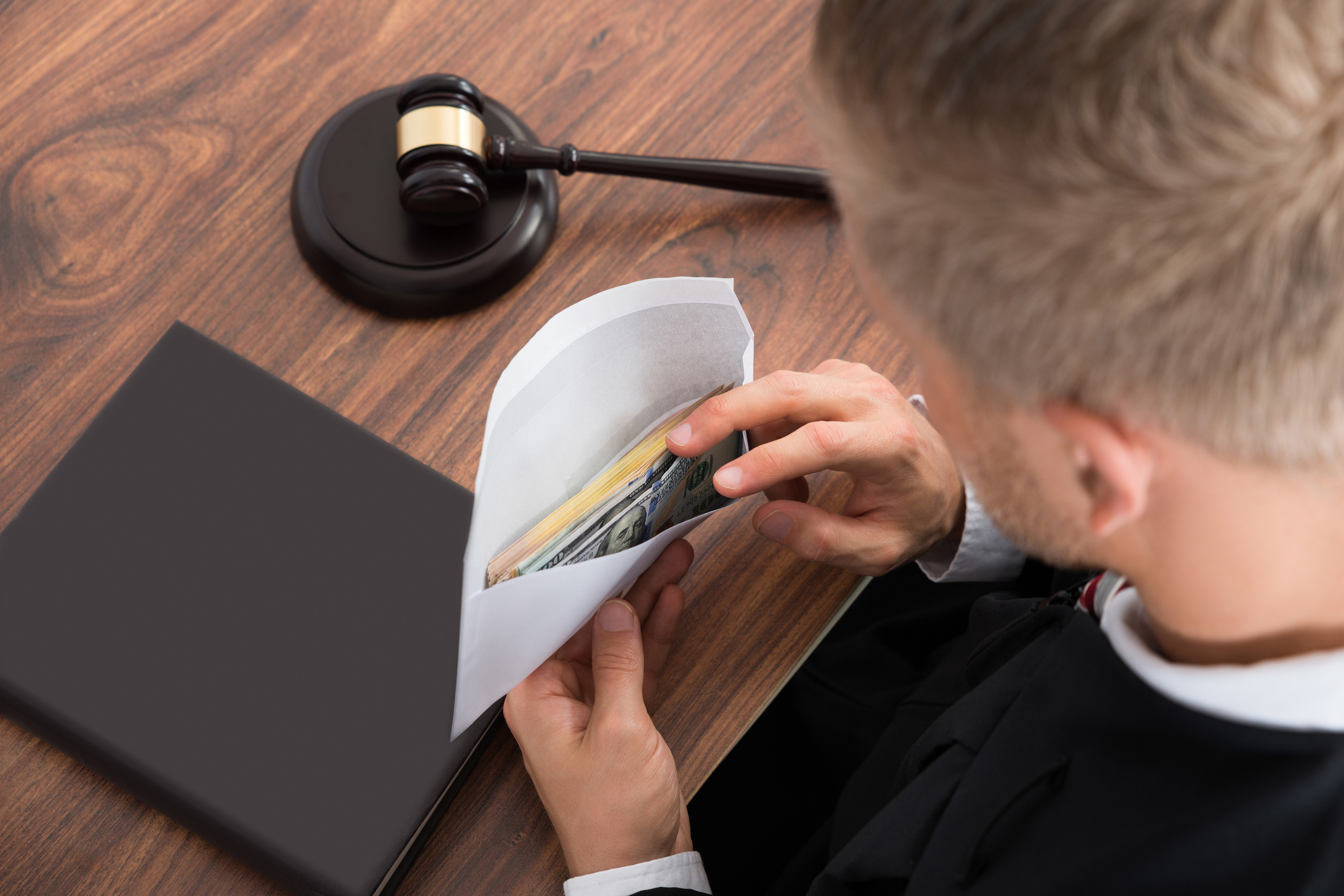 Судија гледа во коверт со пари во судница.