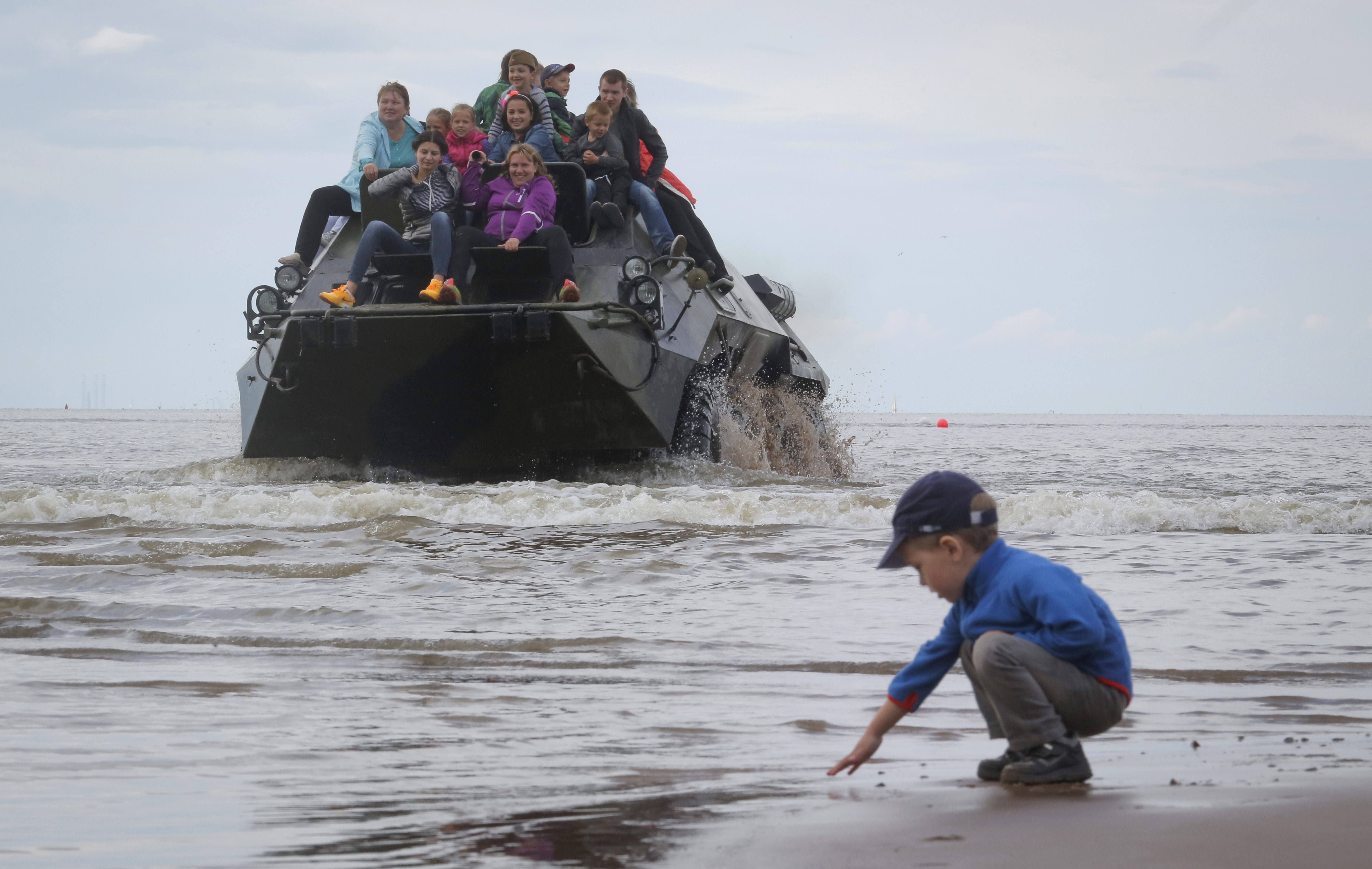 Хора се возят на бронетранспортьор по време на военно шоу във Финския залив.