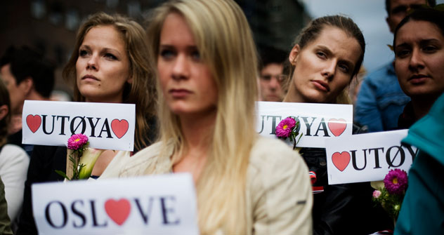 People hold flowers and love "Utoeya" and "Oslove" signs as thousands of people massed outside Oslo's City Hall on July 25, 2011 for a flower-carrying vigil in memory of the 76 victims of last week's twin attacks. Source: AFP/East News