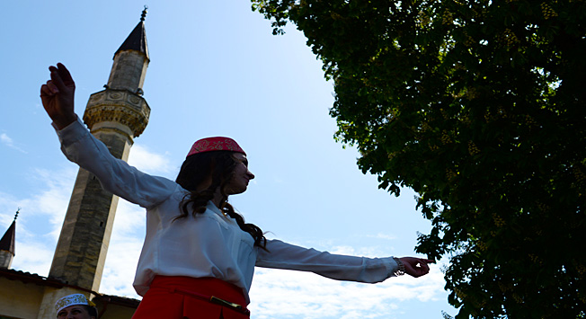Seorang perempuan muda menampilkan tarian tradisional Tatar Krimea di halaman Istana Khan di Bakhchysarai.