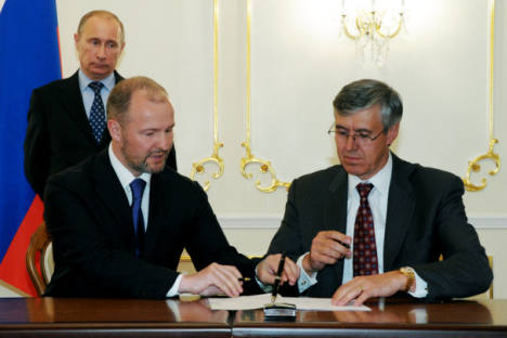 Premiê russo Vladímir Pútin (em segundo plano) durante cerimônia de assinatura de acordos realizada na residência de Novo-Ogariovo. Da esquerda à direita (em primeiro plano), estão os presidentes da United Shipbuilding Corporation, Roman Trotsênko, e