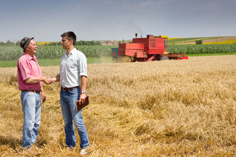 Paysan et homme d'affaires se serrant la main sur un champ de blé.