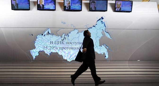 A man walks past a map of Russia and portraits of presidential candidates (L-R) Vladimir Zhirinovsky, Gennady Zyuganov, Sergei Mironov, Mikhail Prokhorov and Vladimir Putin at the Putin's headquarters in Moscow on March 4, 2012. Source: AP