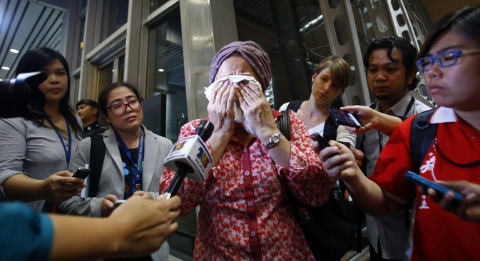 TV journalists try to interview a crying woman as she waits more information about the Malaysian Boeing 777 after it was shot down. Photo: Reuters