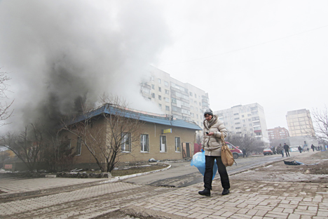 A woman resident passes by a burning house in Mariupol, Ukraine, Saturday, Jan. 24, 2015. Source: AP